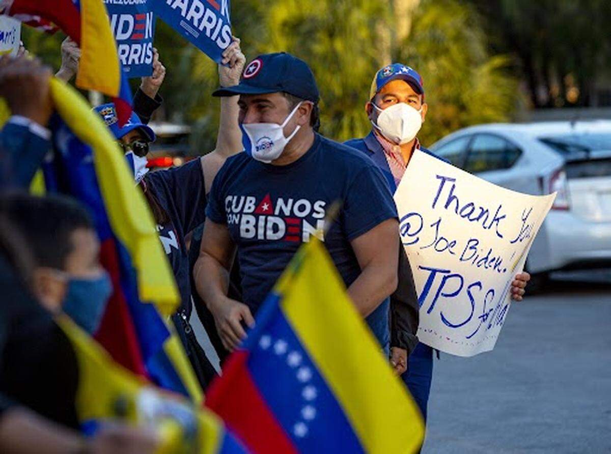 People wave the flag of Venezuela and signs thanking President Joe Biden as they celebrate the approval of temporary protection status for Venezuelan citizens living in the United States, at El Arepazo in Doral, Florida, on Tuesday, Mar., 9, 2021. The Biden administration fulfilled a campaign promise Monday, when it announced TPS for all Venezuelan exiles fleeing the Nicolas Maduro regime in the form of legal rights to live and work in America for 18 months.