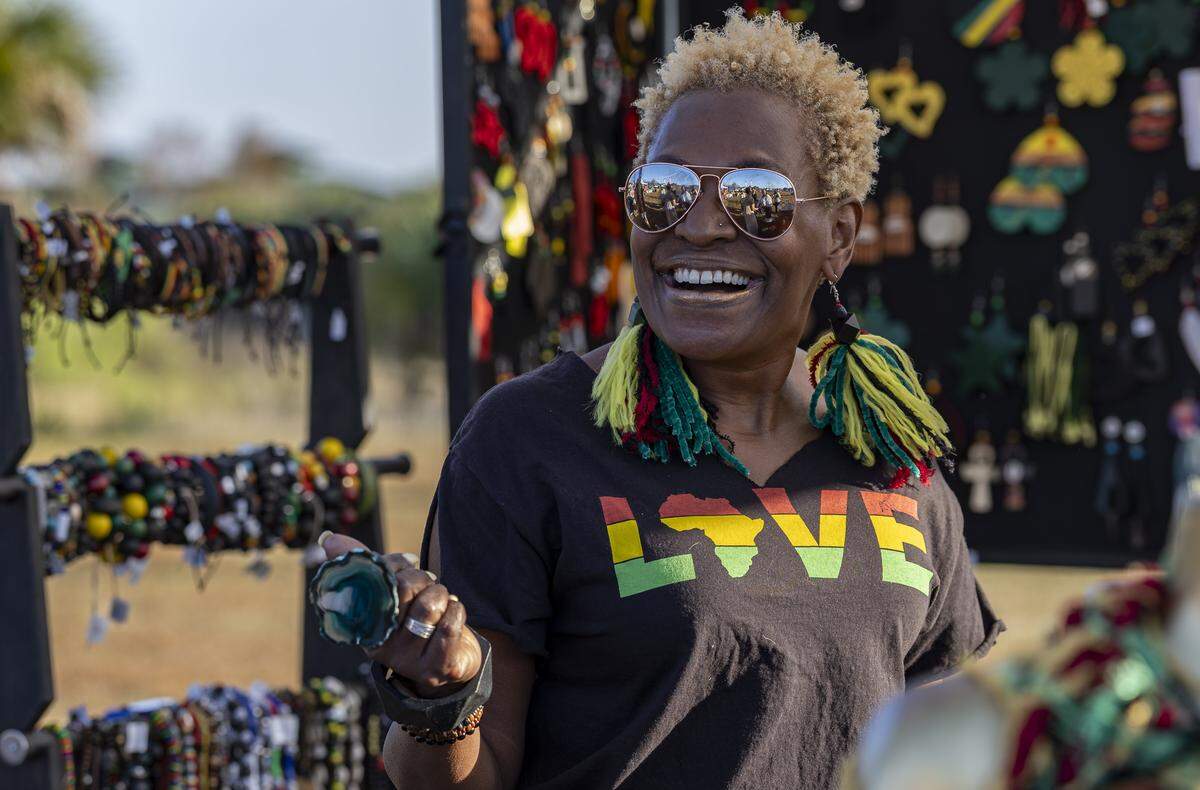 Carmen Puccio, owner of Genesis Unique Jewelry, reacts as she prepares her booth to sell various items at the Reggae Genealogy music festival.