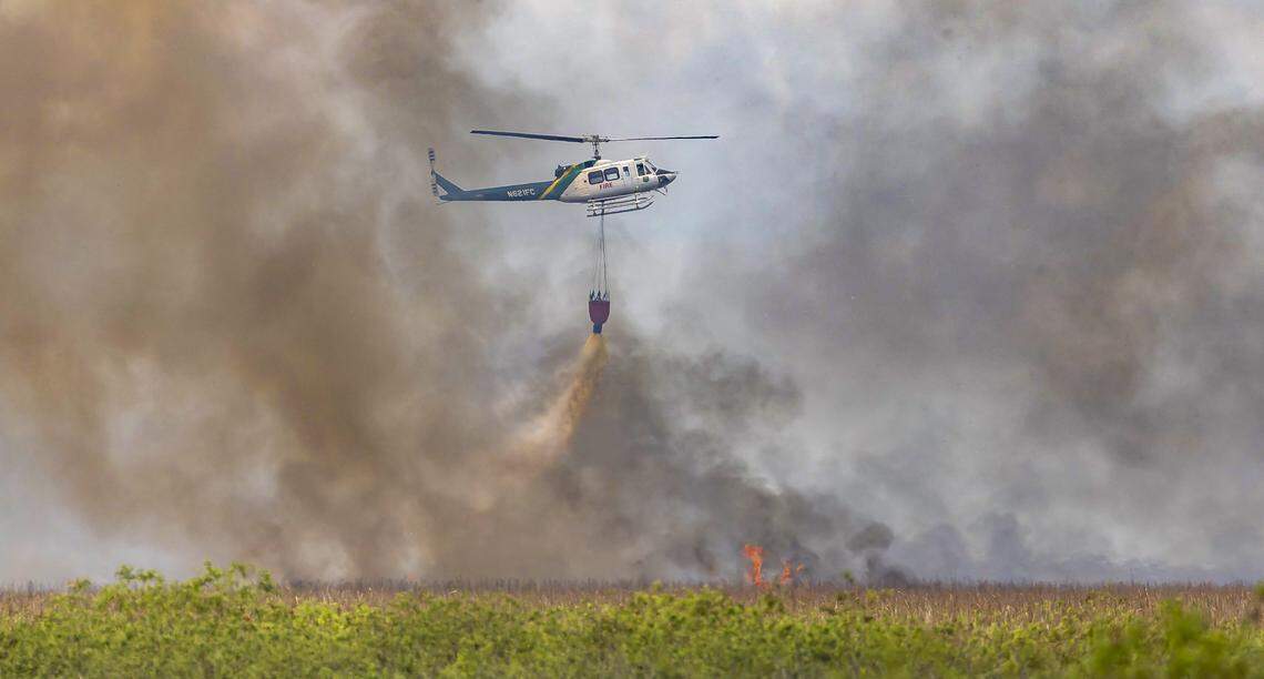  Florida Forest Service firefighters use a helicopter to carry water as they combat an Everglades wildfire near US Highway 27 on Thursday, Aug. 21, 2025, in South Florida.