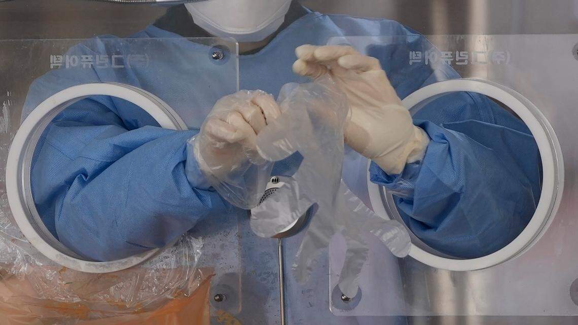 A medical worker wears plastic gloves at a temporary screening clinic for the coronavirus in Seoul, South Korea, Monday, Nov. 29, 2021. The emergence of the new omicron variant and the world’s desperate and likely futile attempts to keep it at bay are reminders of what scientists have warned for months: The coronavirus will thrive as long as vast parts of the world lack vaccines.