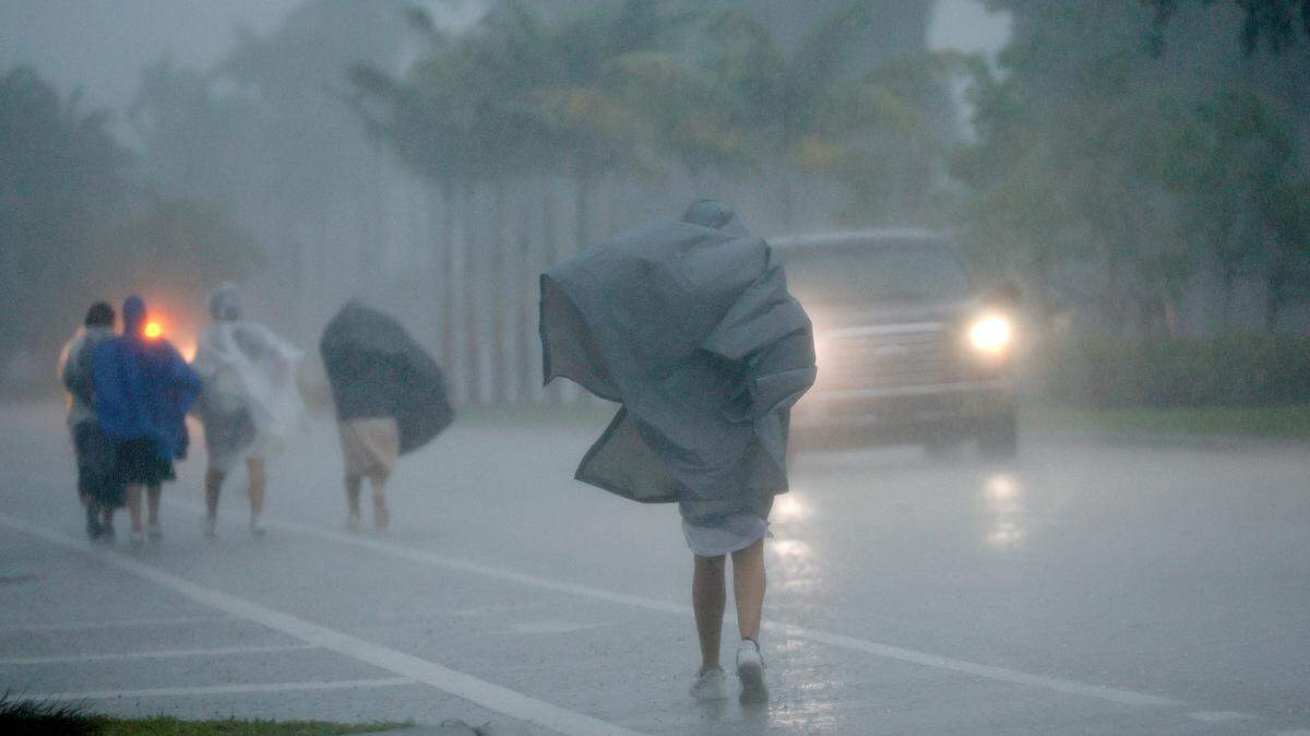 A group of people in raincoats walk east along Hollywood Boulevard in the pouring rain on Wednesday, April 12, 2023.