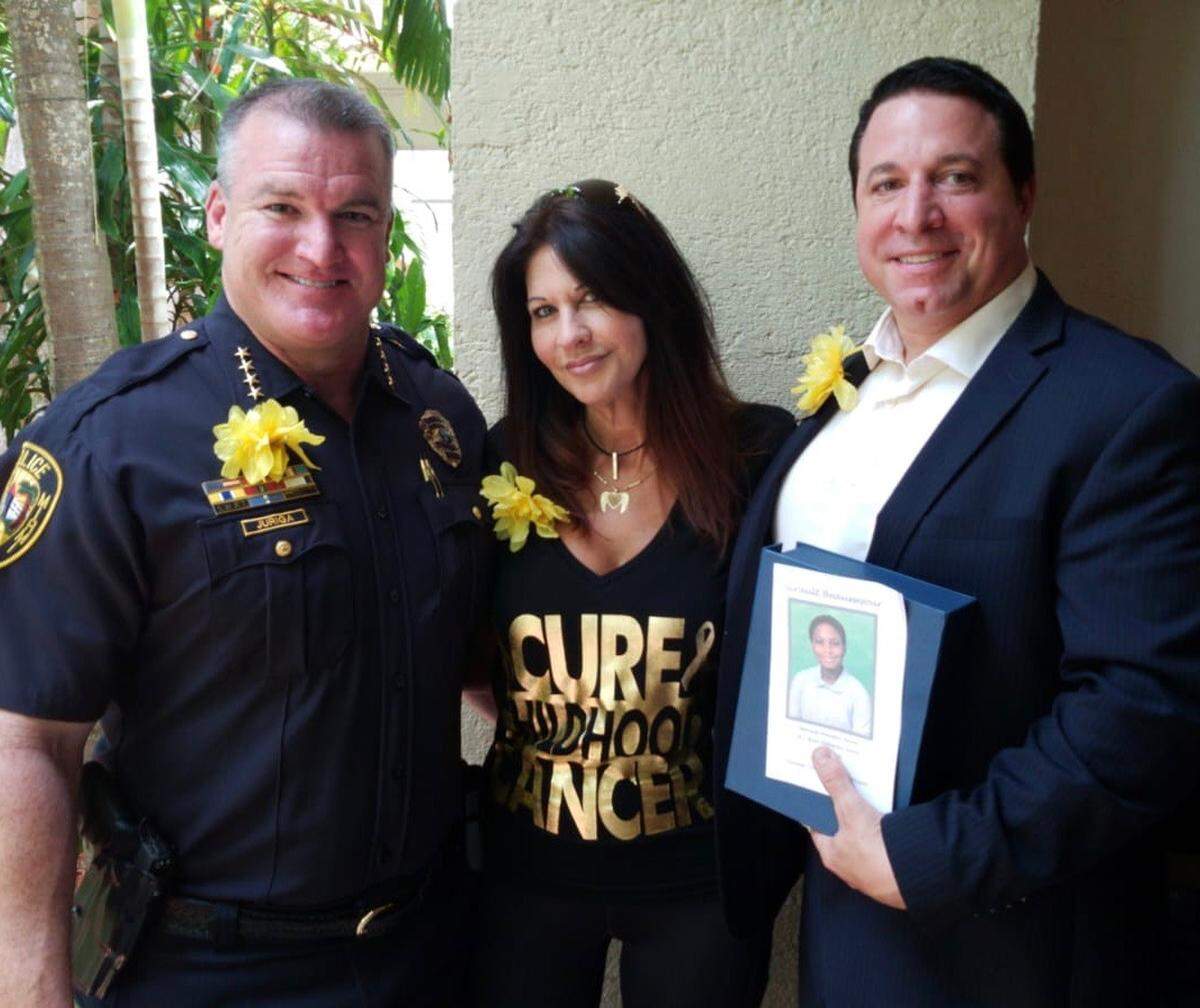 Larry Juriga, North Miami Police chief, stands beside Silvia Vanni, the executive director of the Mystic Force Foundation, and Anthony Damato to honor the life of a William J Bryan High Elementary school student who died of cancer.