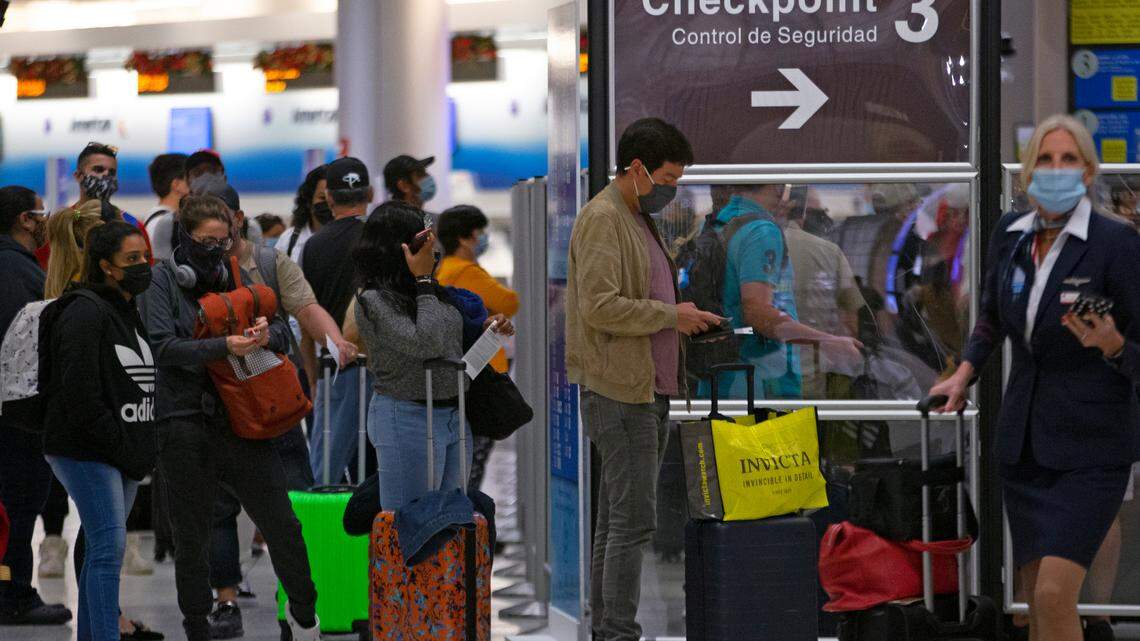 Travelers wearing protective face masks line up to pass through a security checkpoint at Concourse D at Miami International Airport on Monday, Dec. 28, 2020. A survey published in March 2022 found MIA had the longest average wait times for security and passport control among the nation’s largest airports.
