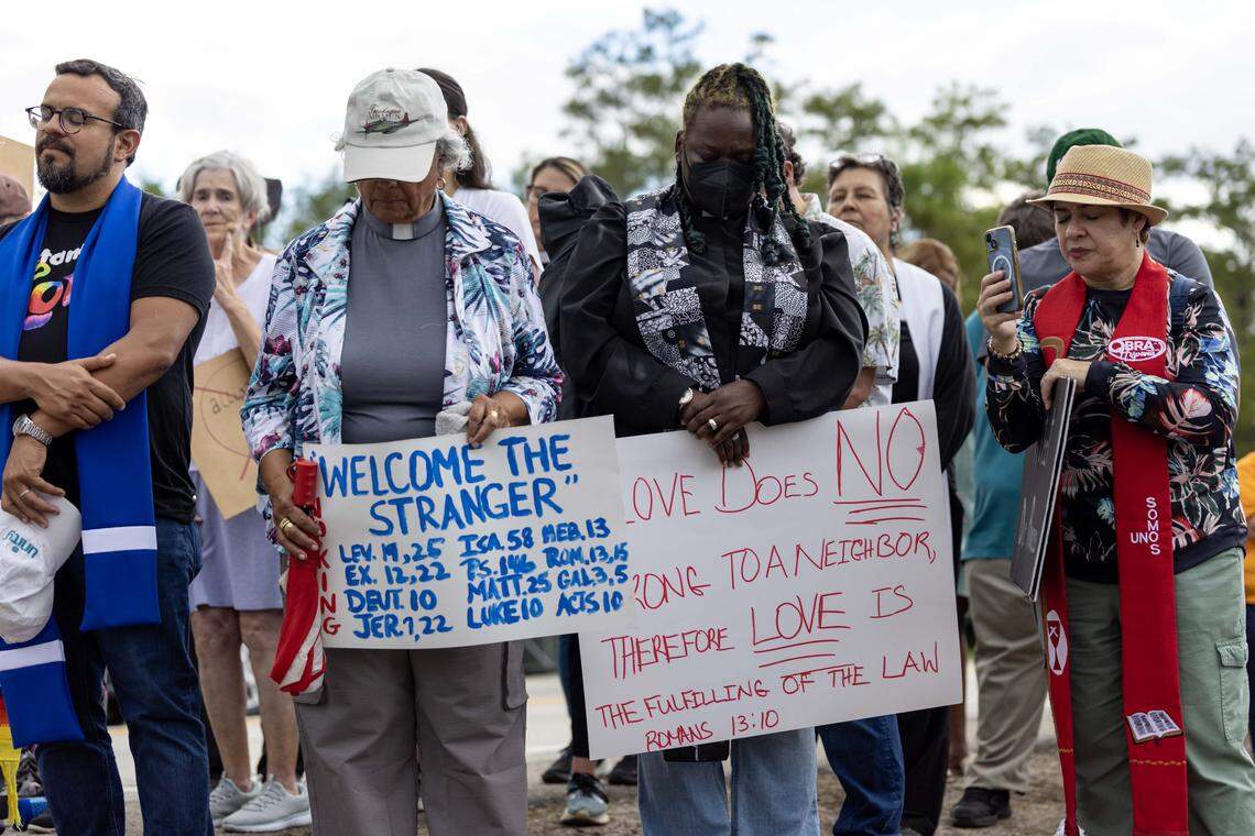 Faith leaders bow their heads in prayer during and interfaith vigil outside Alligator Alcatraz.