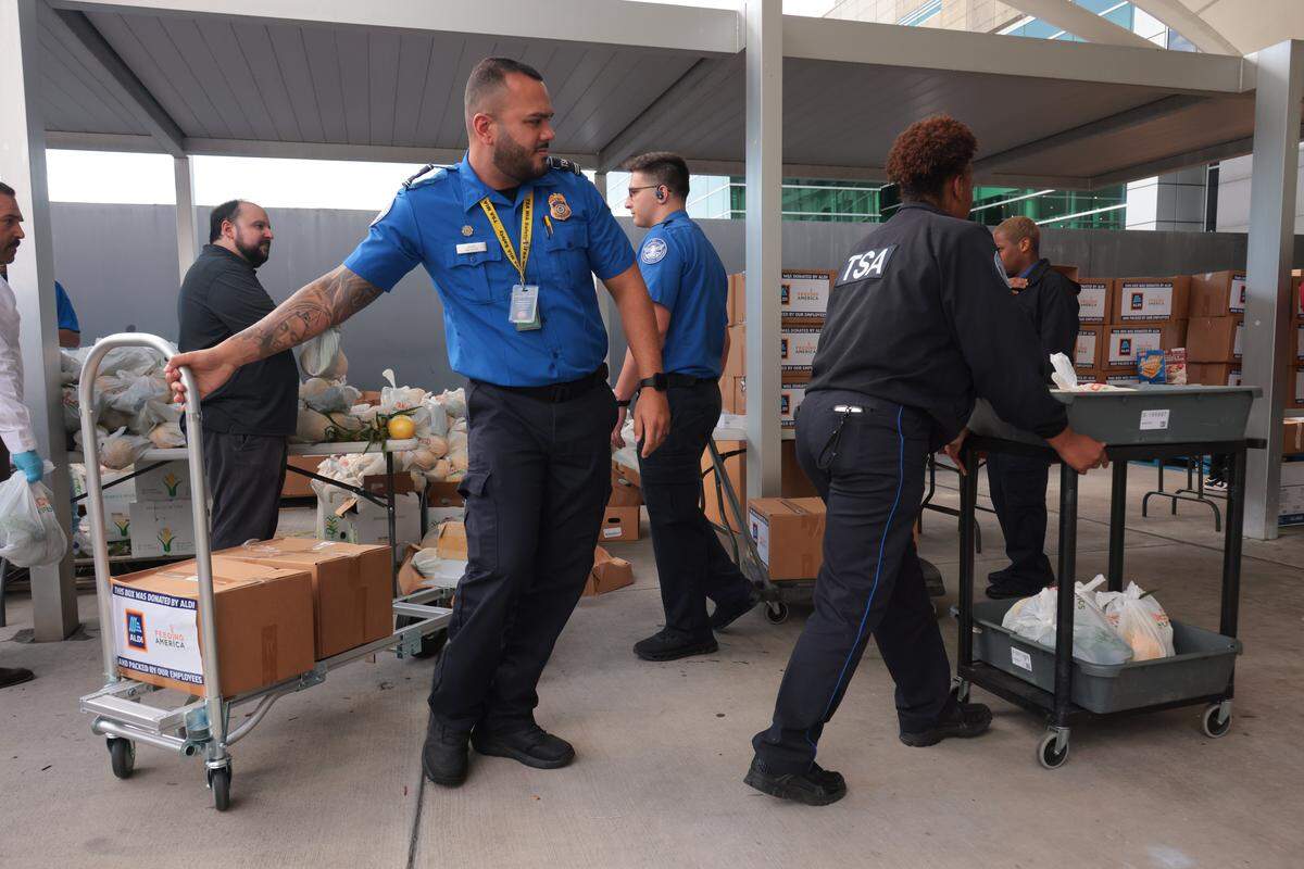 Transportation Security Administration workers impacted by the federal government shutdown collect food items inside a luggage cart at Miami International Airport in Miami, Florida, Friday, October 24, 2025.