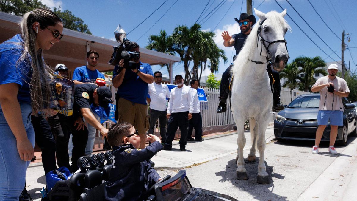 Franco Bernal, center, 6, battling childhood leukemia, waves to a City of Miami Police officer on a horse during his Wish Reveal on Thursday, July 18, 2024, with Make-A-Wish and City of Miami Police in Miami. Bernal loves the police and Disney World, and so they organized a parade to announce that his wish to go to Disney World is being granted next week.