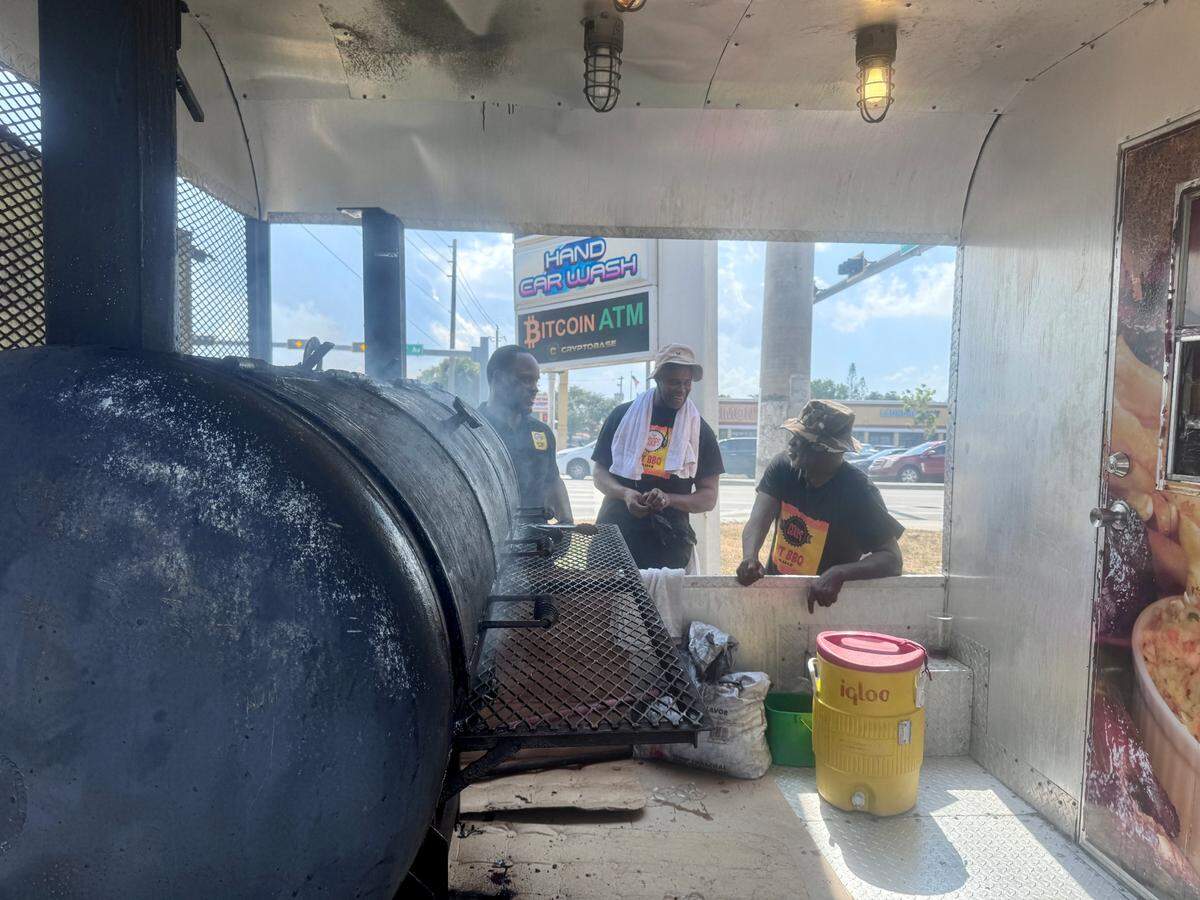 Brothers Torris Cooper (left) and Rhaudal Cooper Jr. (center) stand next to their father, Rhaudal Cooper Sr. (right) behind their family-owned and operated food truck, Coop’s BBQ Pit, on Wednesday, May 29, 2024 in Miami, Florida. Coop’s BBQ Pit, which the trio owns alongside Kelvin Cooper, received the Keith Lee stamp of approval thanks to the food blogger’s review that was posted Tuesday on TikTok.
