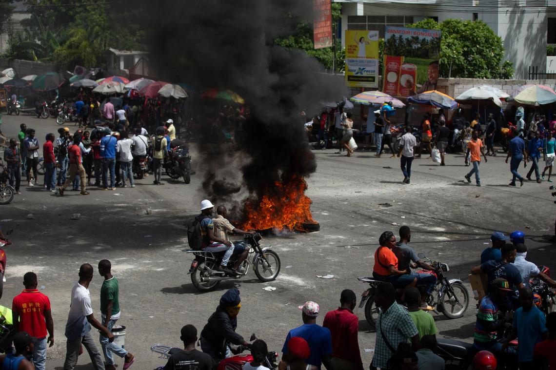 People walk around burning tires set up by taxi drivers to protest the country’s fuel shortage in Port-au-Prince, Haiti, Wednesday, July 13, 2022.