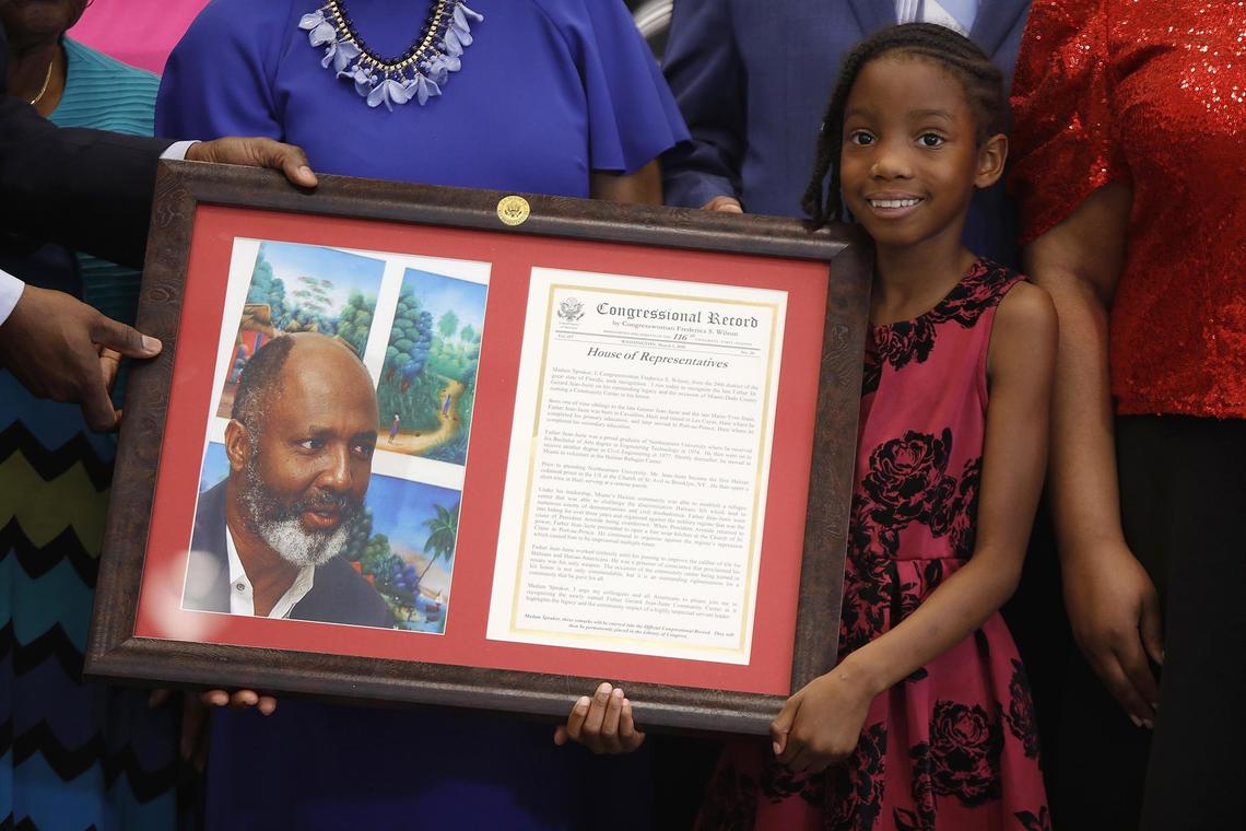 Clover Delica, 8, holds an image of the Rev. Gérard Jean-Juste at the opening of a new community center named in his honor at Oak Grove Park in North Dade on Friday April 5, 2019.
