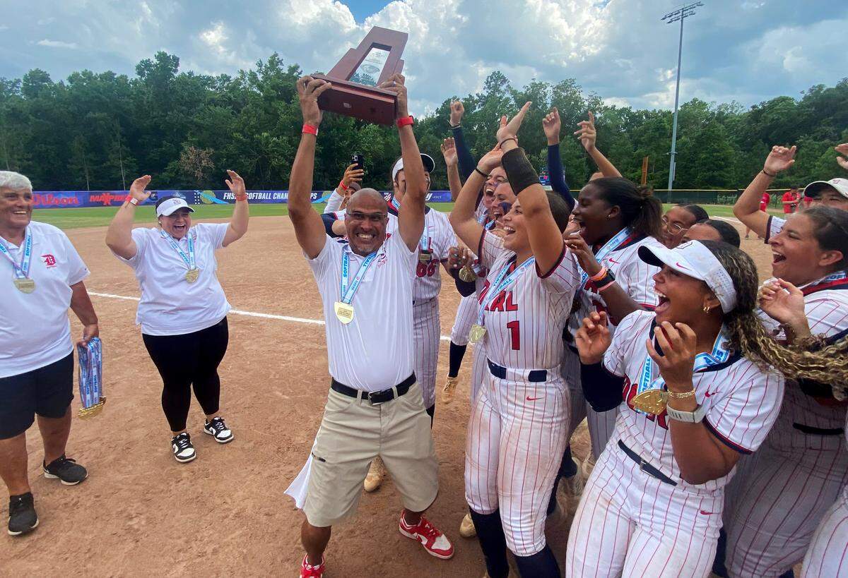 Doral Academy softball coach Willie Viruet celebrates with his players after winning the FHSAA Class 6A state softball title on Saturday at Solider’s Creek Park in Longwood. Doral defeated defending state champions Pace 1-0.