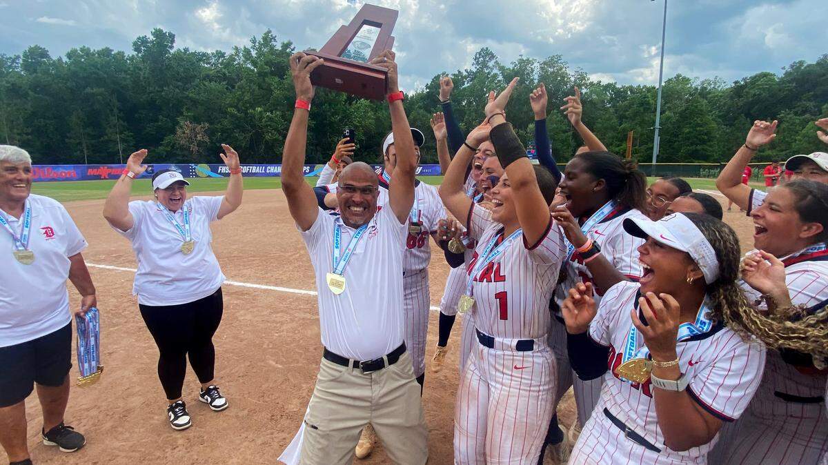 Doral Academy softball coach Willie Viruet celebrates with his players after winning the FHSAA Class 6A state softball title on Saturday at Solider’s Creek Park in Longwood. Doral defeated defending state champions Pace 1-0.