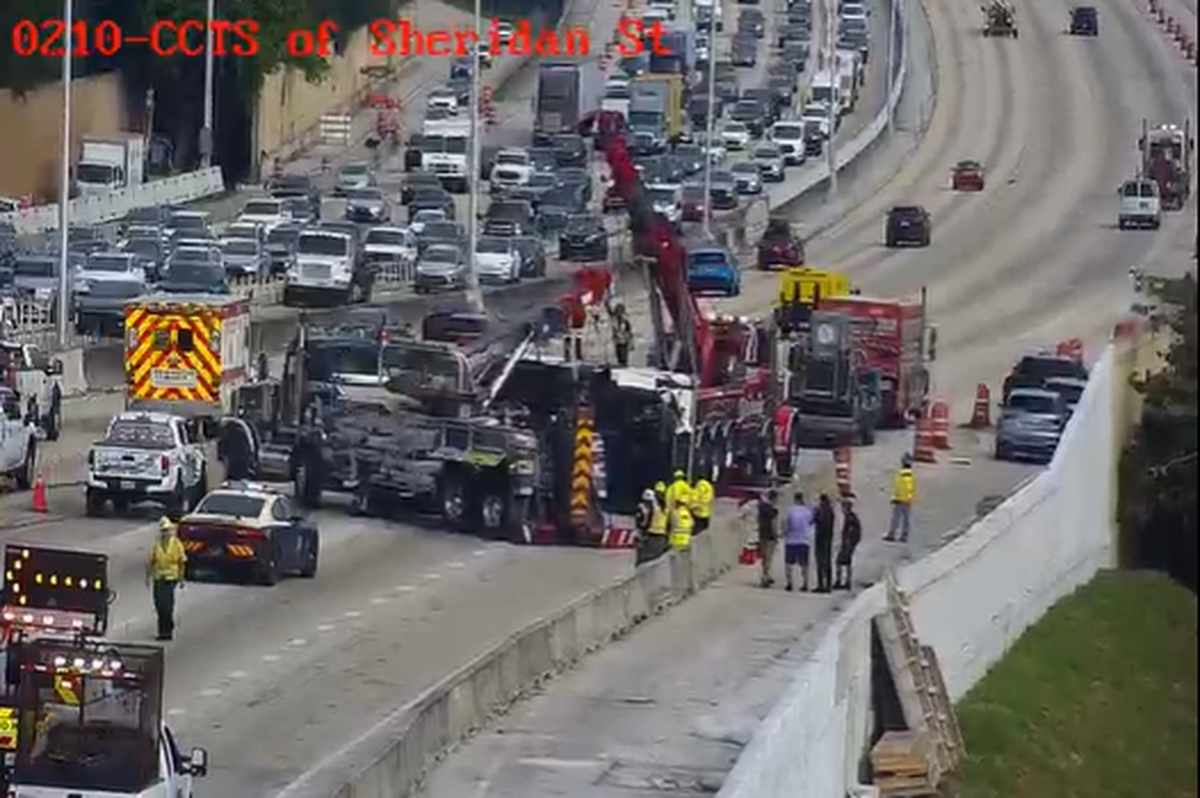 Heavy-duty tow trucks try lifting large vehicle that flipped on its side and blocked several northbound lanes of Interstate 95 near Hollywood, Florida, on the morning of Friday, Dec. 8, 2023.