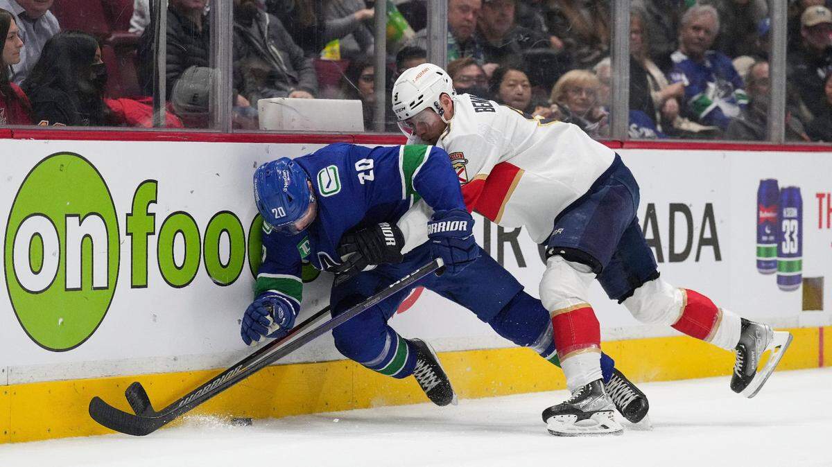 Florida Panthers’ Sam Bennett (9) checks Vancouver Canucks’ Curtis Lazar (20) during the first period of an NHL hockey game Thursday, Dec. 1, 2022, in Vancouver, British Columbia.