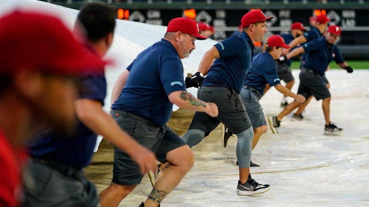Members of the grounds crew pull a tarp over the field ahead of a baseball game between the Philadelphia Phillies and the Miami Marlins, Tuesday, Aug. 9, 2022, in Philadelphia. (AP Photo/Matt Rourke)
