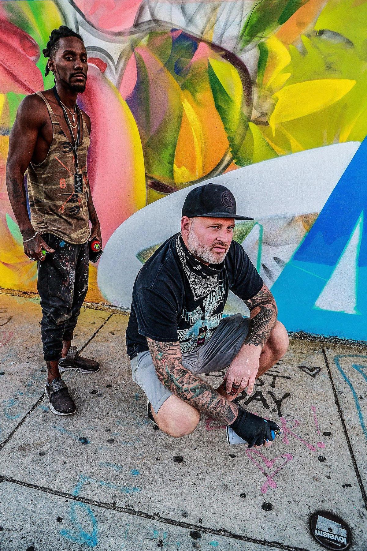 The veteran Miami graffiti artist known as Quake, right, working in collaboration with fellow street artist Hiero, pause while they spray-paint a mural on Northwest 26th Street at Wynwood Walls. Quake won a locals-only commission to paint the prominent wall for Miami Art Week.
