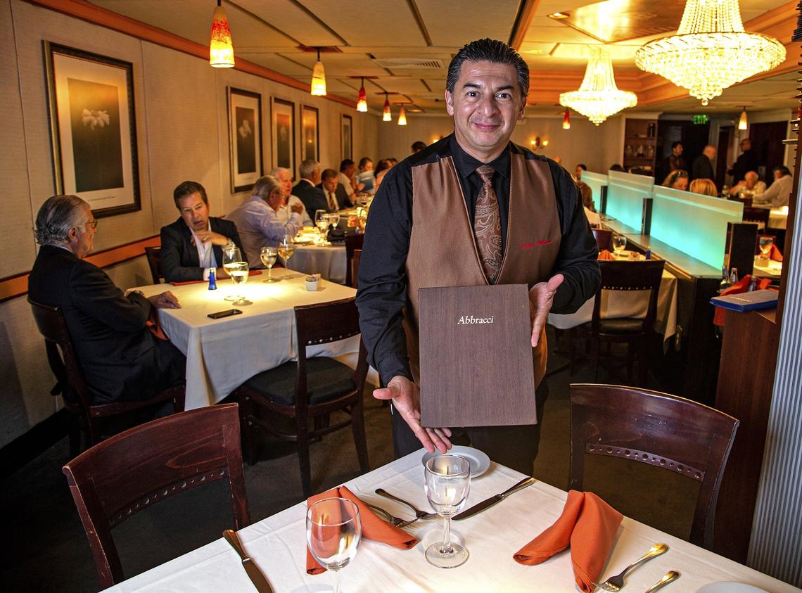 Waiter Mario Troncoso of Caffe Abbracci, stands by the best table in the house on Tuesday, July 16, 2019. The restaurant is celebrating 30 years in the business in Coral Gables.