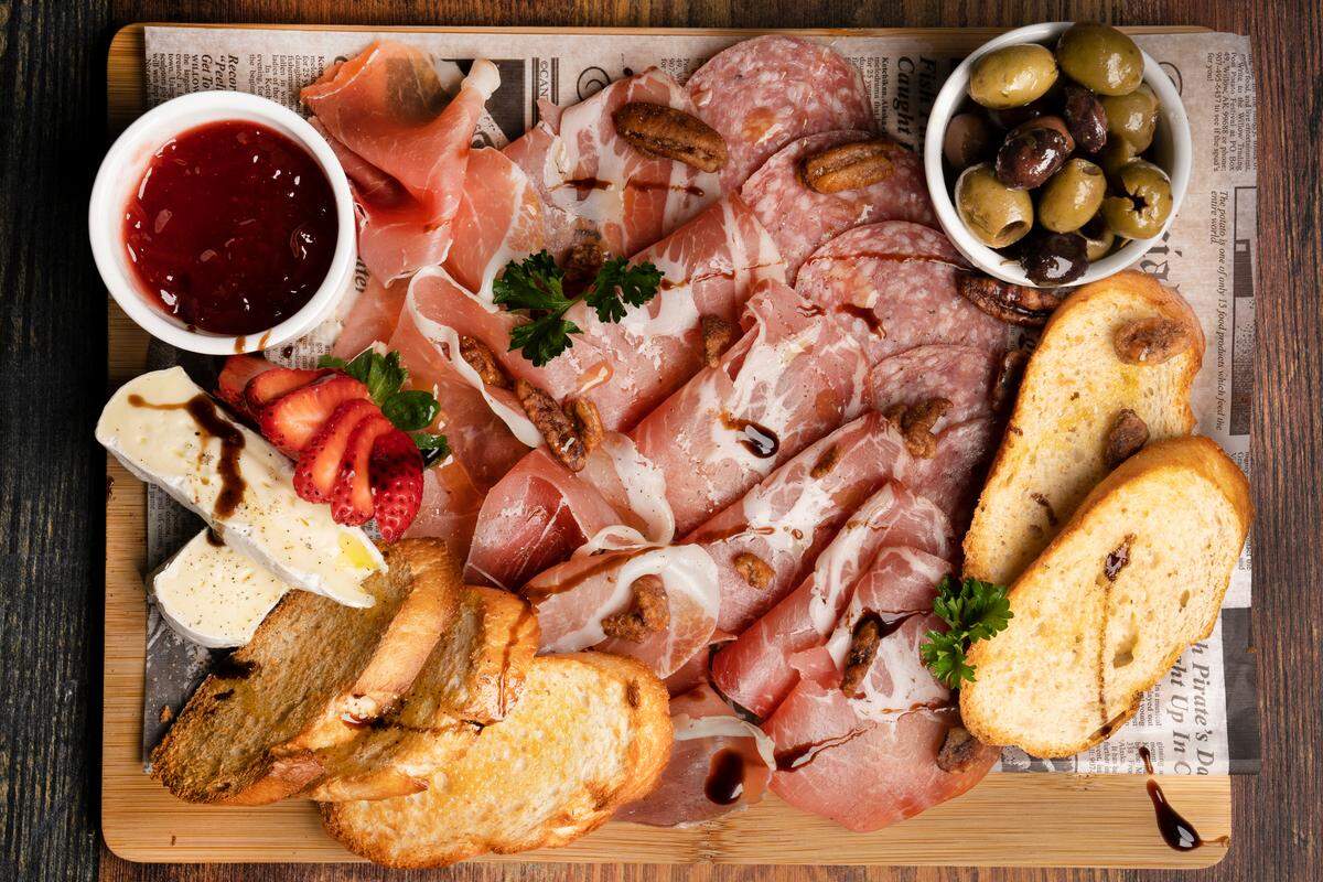 Tablita de Picada con jamón serrano, soppressata de salami, carne de coppa, pimientos rojos asados y aceitunas en KAO Bar & Grill.