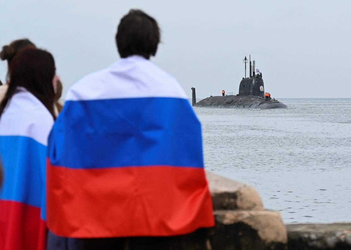 Personas con banderas rusas observan la llegada al puerto de La Habana del submarino nuclear ruso Kazan, parte del destacamento naval ruso que visita Cuba, el 12 de junio de 2024. (Foto de YAMIL LAGE/AFP vía Getty Images)