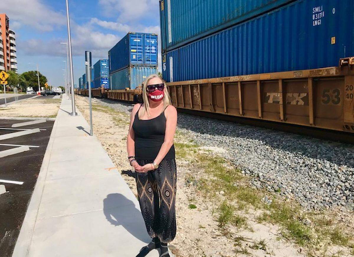 Dr. Kim Jacobsen stands on the new sidewalk along Northeast Fourth Avenue as a train goes by. She thinks there should be a fence separating the railroad tracks from the sidewalk. (Linda Robertson)
