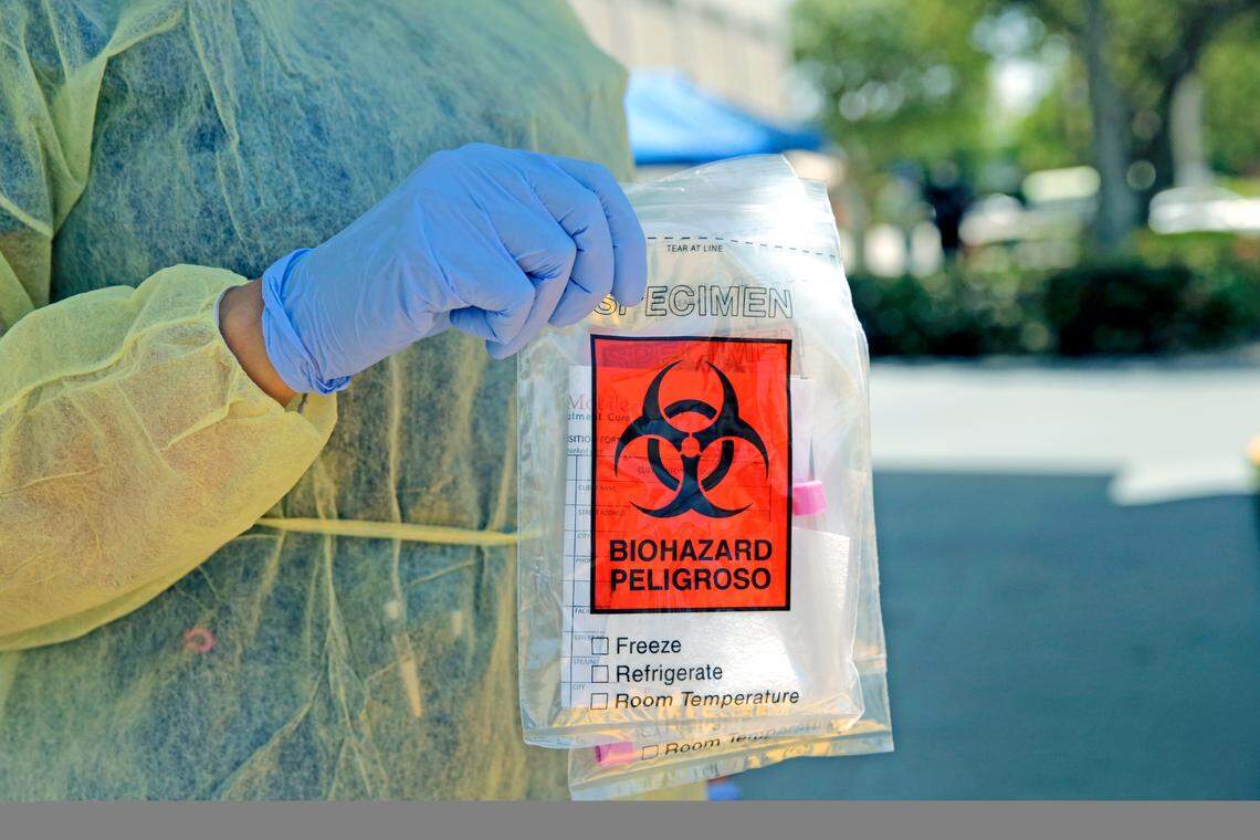 A Florida Department of Health worker holds a swab test from a citizen at the COVID-19 testing mobile lab operated by StatLab Mobile at Residential Plaza for Elderly at Blue Lagoon in Miami on May 7, 2020.