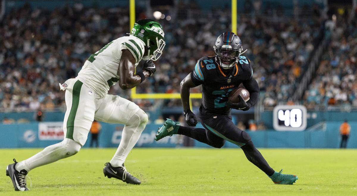 Miami Dolphins running back De'von Achane (28) runs with the ball as New York Jets cornerback Brandon Stephens (21) defends in the first half of their NFL game at Hard Rock Stadium on Monday, Sept. 29, 2025, in Miami Gardens, Fla.