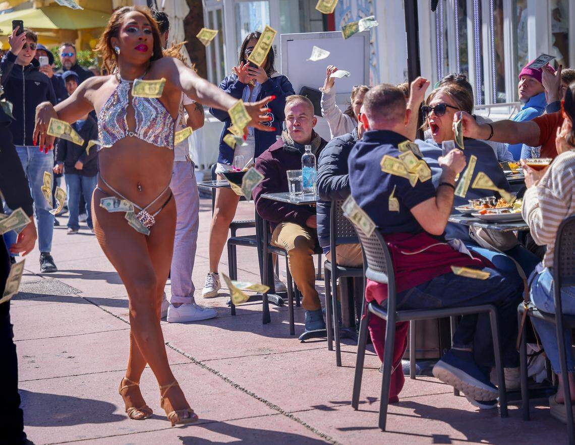 Cabaret performer makes it rain with donated dollar bills during a lip sync performance at the popular Palace Bar and Restaurant during its drag brunch.  Tourists react as they dined, cheered, and walked while a cold snap descended on S. Florida during their visit to Miami Beach’s Art Deco District.Temperatures in South Florida dipped overnight as the polar vortex brought an Arctic blast and cold air. With a high of 56 degrees, residents and visitors swapped shorts, bikinis, and activewear for hoodies, sweaters, and jackets on Sunday, February 1, 2026, in Miami Beach, Florida.
