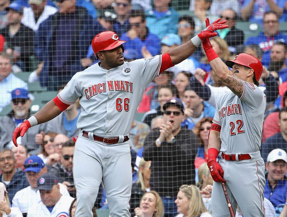 Yasiel Puig # 66 de los Rojos de Cincinnati celebra con Derek Dietrich # 22 luego de batear un jonrón remolcador de dos carreras en la sexta entrada contra los Cachorros de Chicago en Wrigley Field el 24 de mayo de 2019 en Chicago, Illinois.
