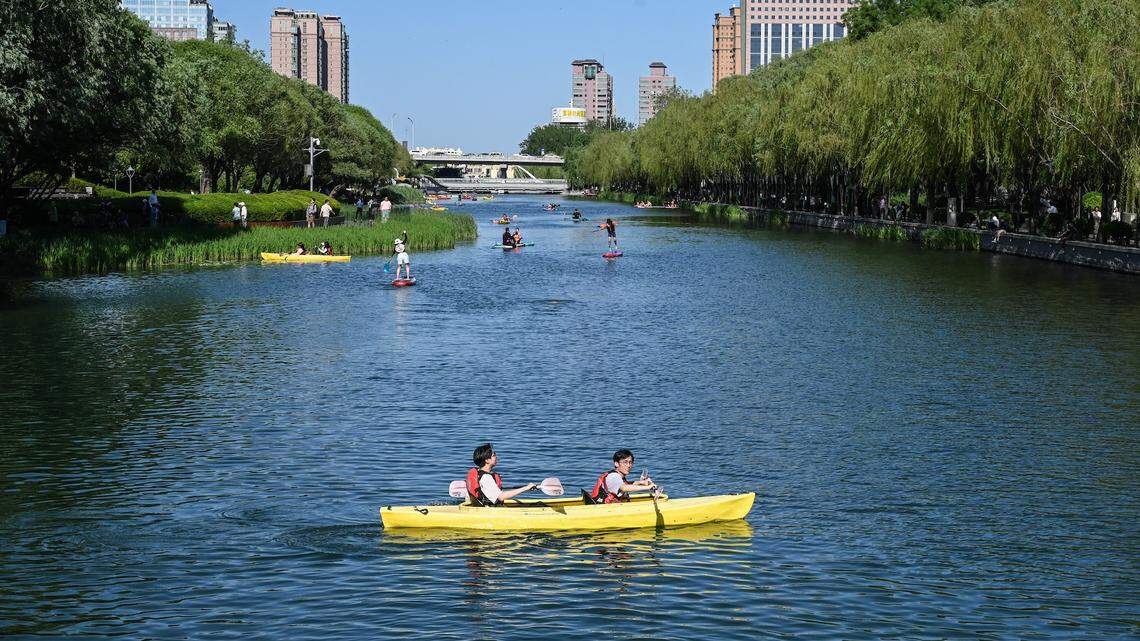 People paddle a kayak on a canal in Beijing on May 12, 2024. (Photo by JADE GAO / AFP)