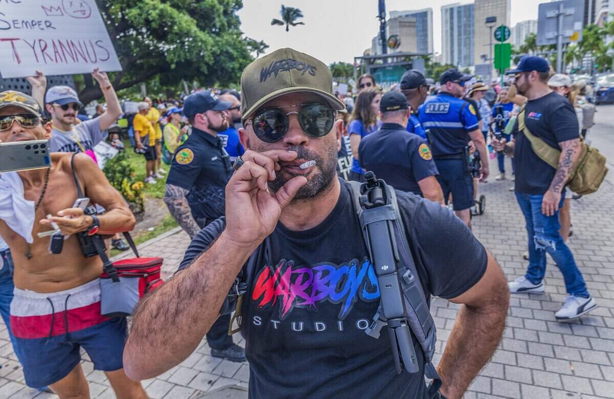 El exlíder de Proud Boys, Enrique Tarrio, fuma un cigarro mientras se aleja después de que algunos manifestantes se le acercaran en la Antorcha de la Amistad, en el centro de Miami, durante las protestas “Sin Reyes” contra Trump el 18 de octubre.