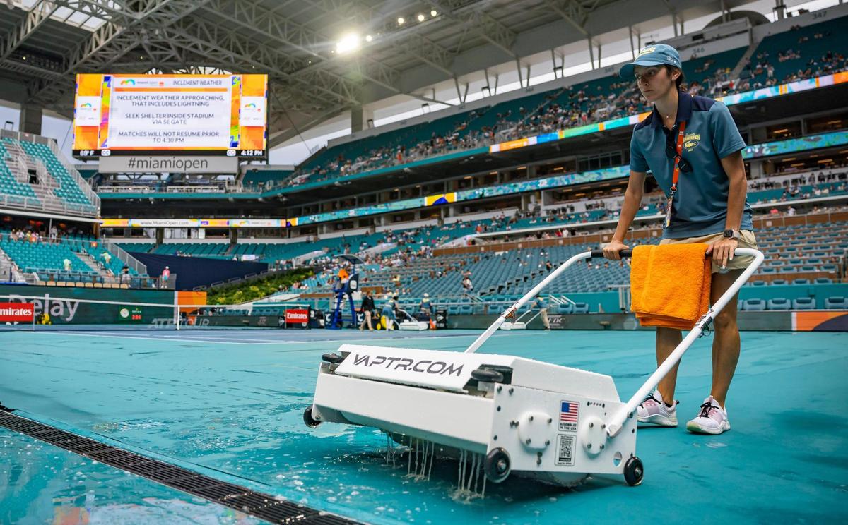 A crew member works to dry the court as a rain delay postpones the Miami Open tennis tournament on Tuesday, March 25, 2025, at Hard Rock Stadium in Miami Gardens, Fla.