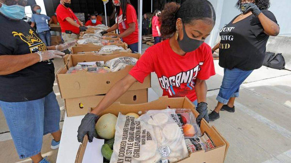 Yahne Jackson, Communication Workers of America Union member  takes a box of food to waiting cars during a food drive in July. Miami-Dade saw the number of people using food banks skyrocket because of the COVID-19 pandemic. 