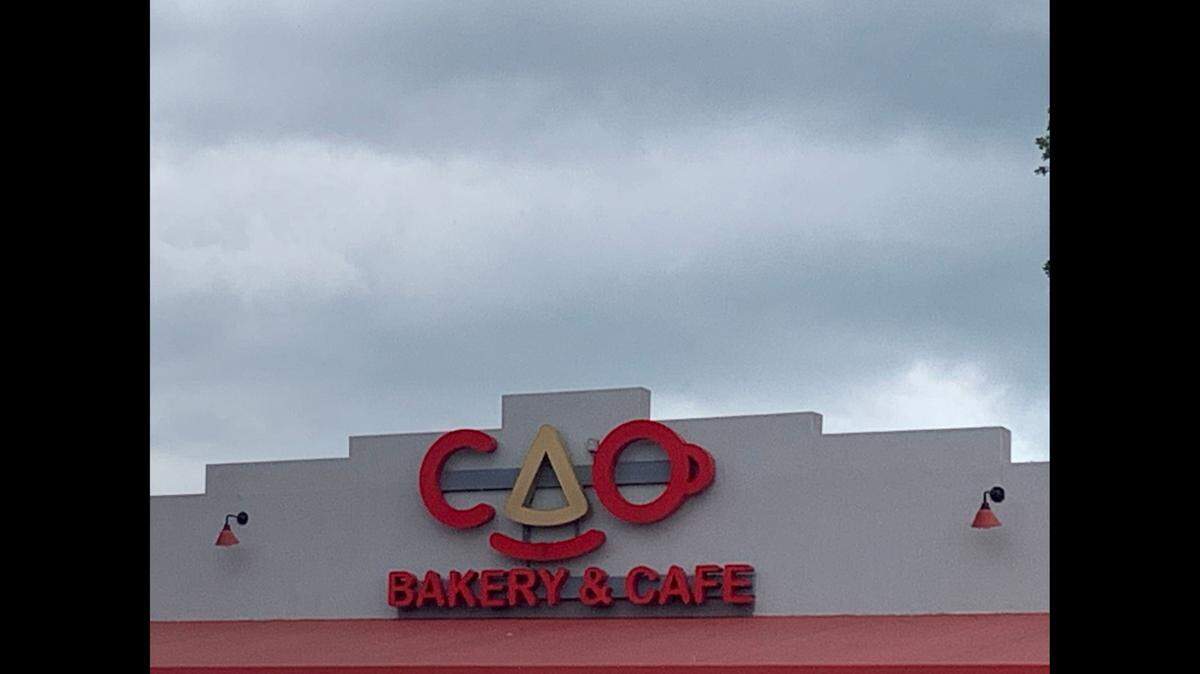 Was the “gray and black mold-like grime” in the mojo at a Miami area CAO Bakery & Cafe as gray as the clouds over this CAO Bakery’s sign?