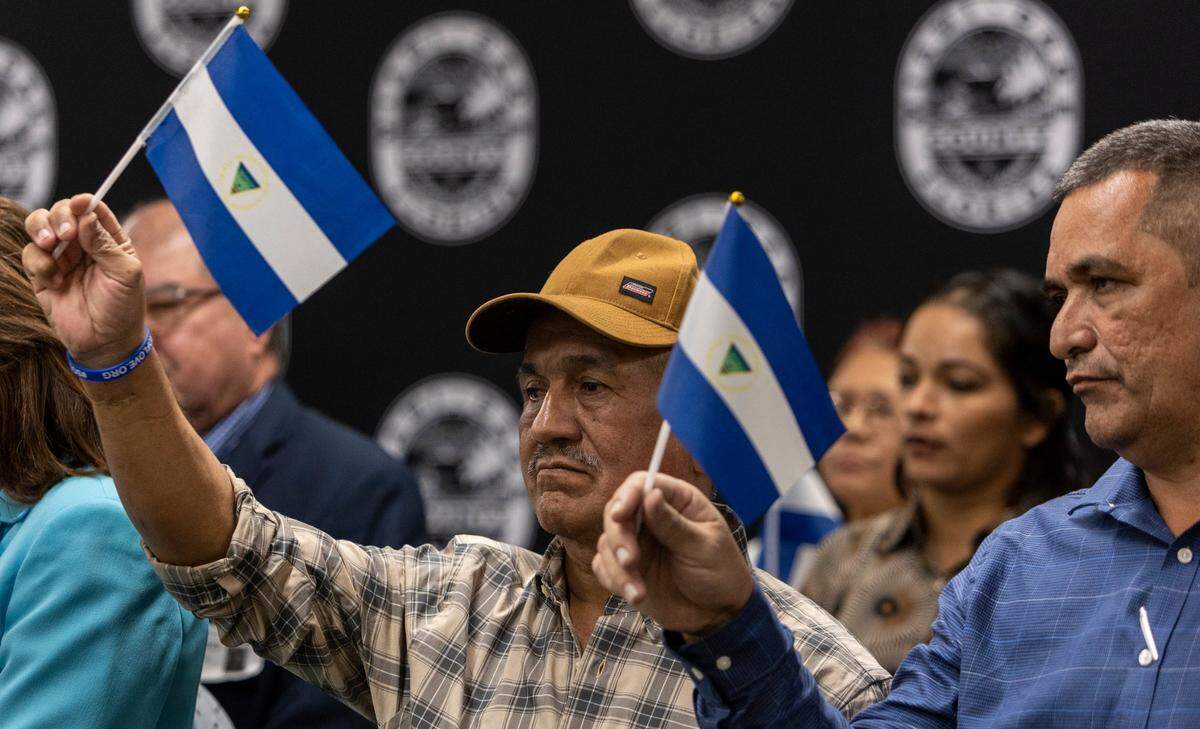 Former Nicaraguan political prisoners Victor Manuel Sosa Herrera, left, and Armando Robles Alaniz, right, in February 2023 raise their country’s flag to protest the authoritarian regime.