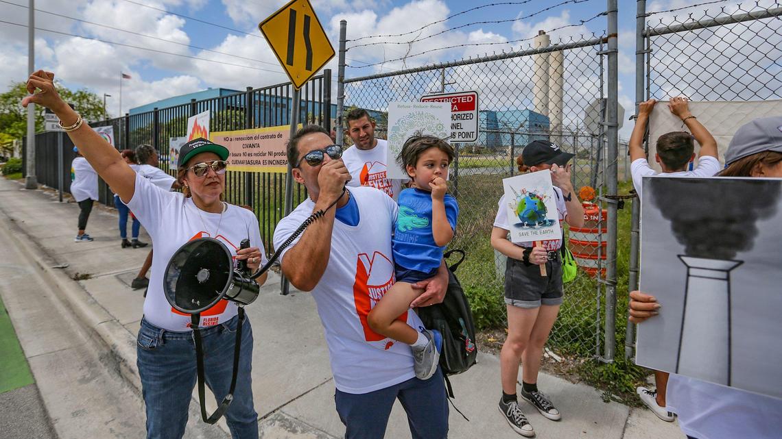 Gina Romero flashes a thumbs down as Alexandro Fung chants on a speaker as Doral residents protest against a new garbage incinerator the county is considering in Doral, Florida, on Saturday, April 23, 2022. The current incinerator is up for renewal.