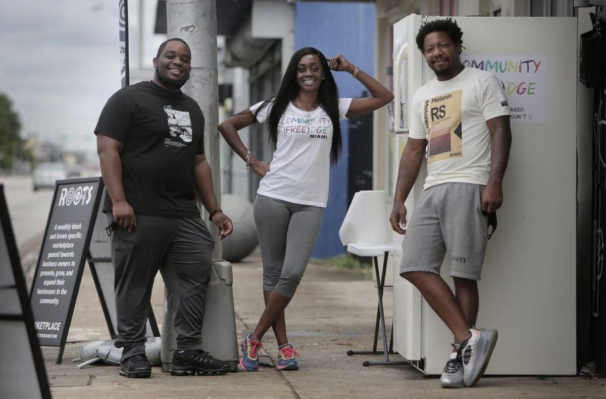 Isaiah Thomas, left, Sherina Jones and the late Danny Agnew by the refrigerator they placed in front of the Roots Collective to provide free food to locals.