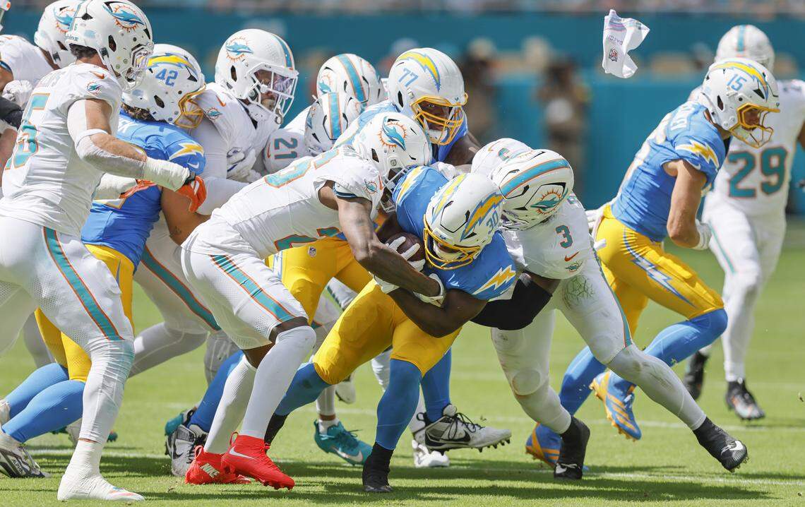 Miami Dolphins cornerback Rasul Douglas (26) and linebacker K.J. Britt (3) take down Los Angeles Chargers running back Kimani Vidal (30) in the first half during their NFL football game at Hard Rock Stadium in Miami Gardens, FL, on Sunday, October 12, 2025.
