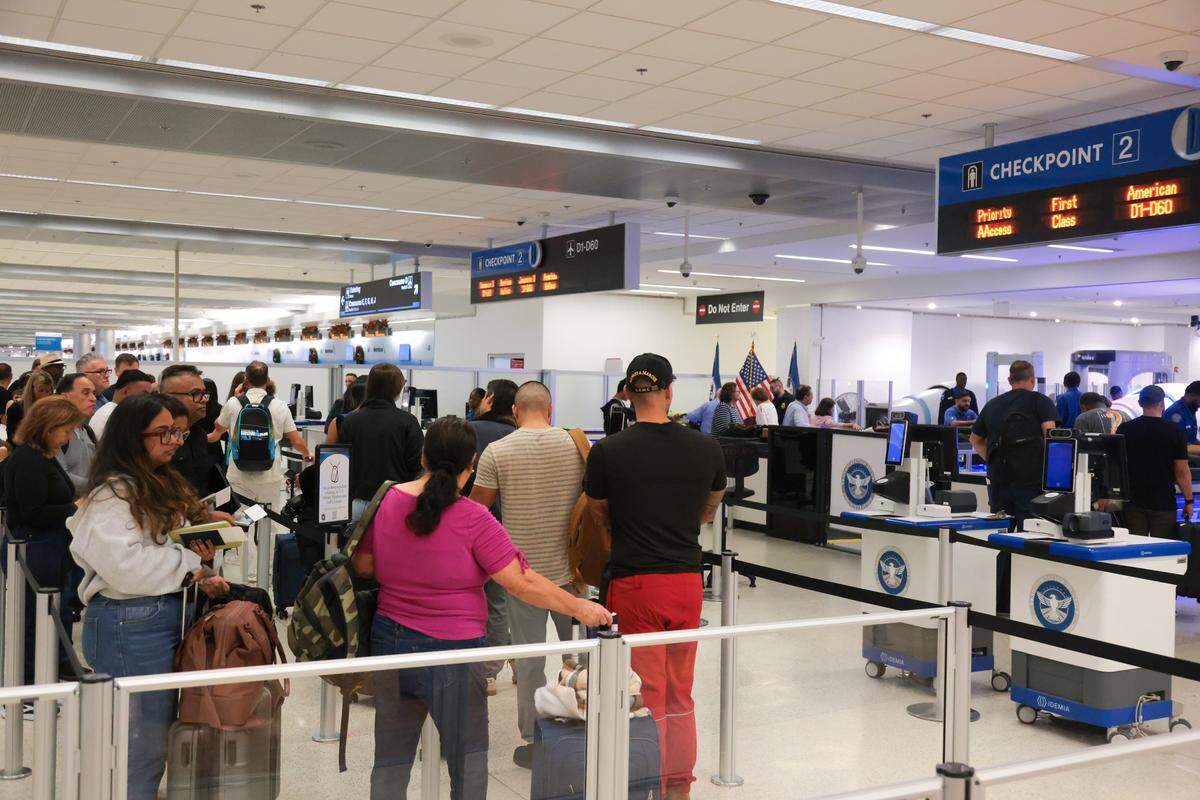 Travelers wait in line before going through security at TSA checkpoint 2 at Miami International Airport on Tuesday, Nov. 25, in Miami, Fla.