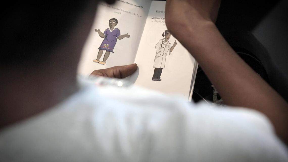 A female factory worker in Port-a-Prince, Haiti, looks through an information booklet on preventing cervical cancer while a midwife (not pictured) talks about using a self-sampler to test for HPV, the virus that’s the principal cause of the disease.
