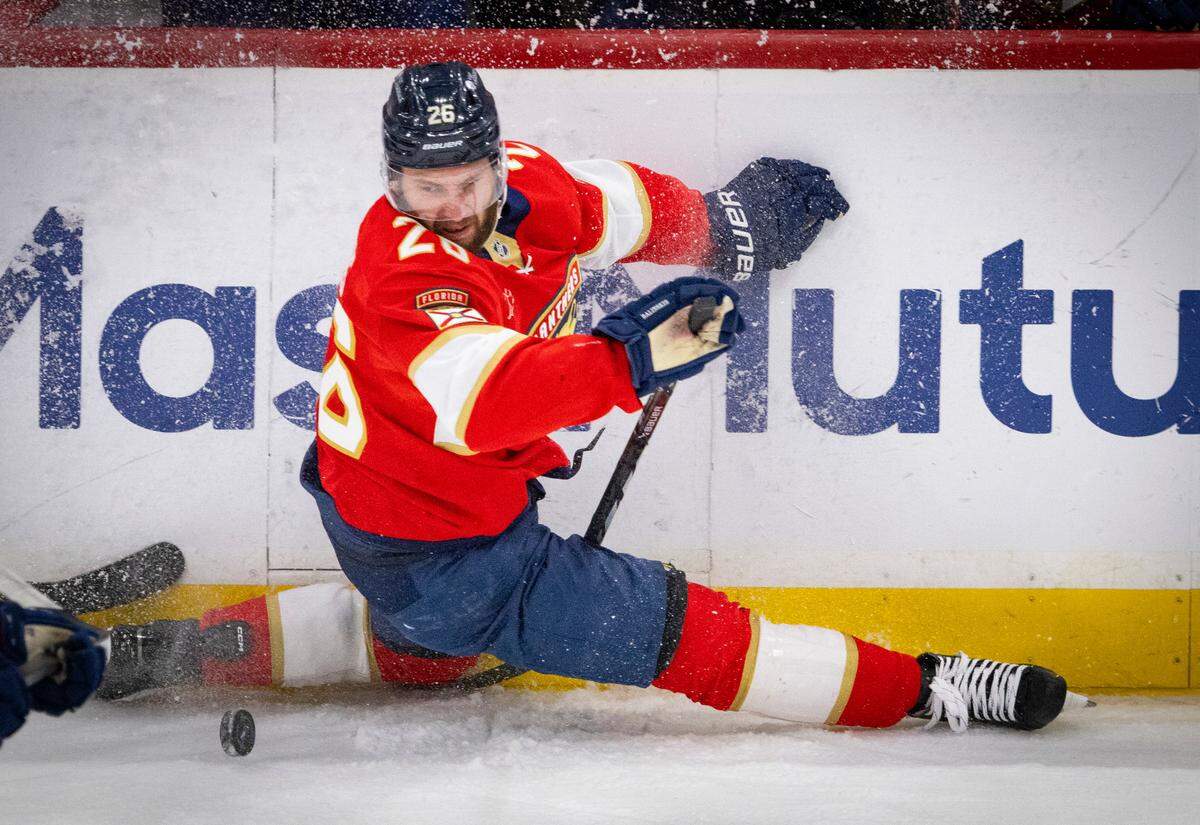 Florida Panthers defenseman Uvis Balinskis (26) falls while taking a shot around Carolina Hurricanes center Sebastian Aho (20) in the first period of Game 4 during the Eastern Conference final of the NHL Stanley Cup playoffs at the Amerant Bank Arena on Monday, May 26, 2025 in Sunrise, Fla.