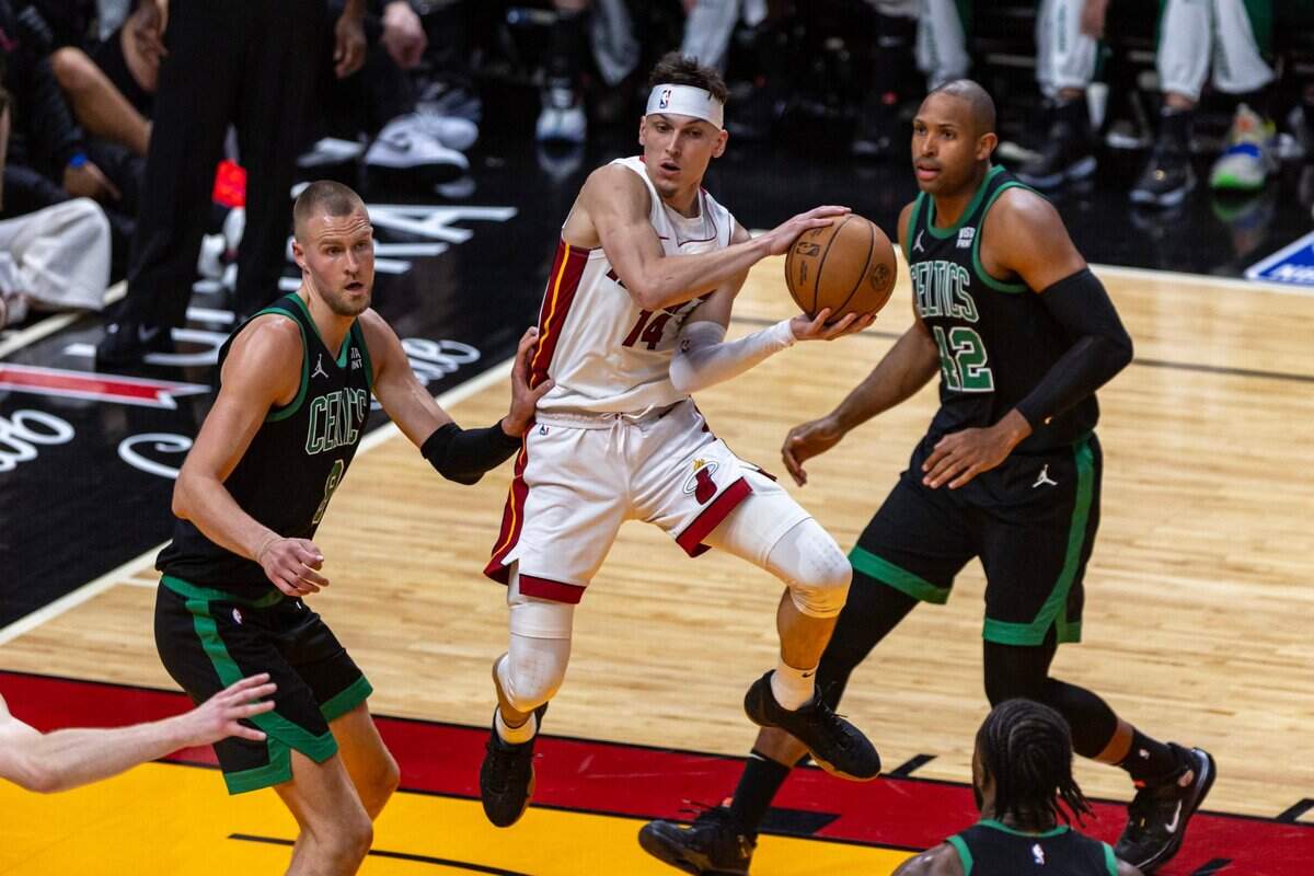 Miami Heat guard Tyler Herro (14) hangs in the air as he looks to pass while defended by Boston Celtics center Kristaps Porzingis (8) during the second half of Game three of an NBA basketball first-round playoff series at Kaseya Center in Miami, Florida, on Saturday, April 27, 2024.
