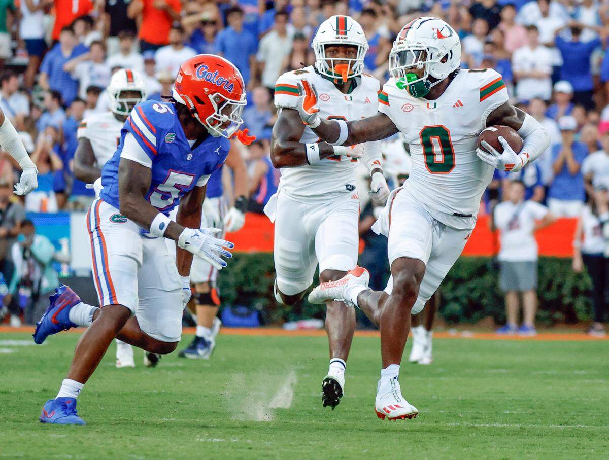 Miami Hurricanes defensive back Mishael Powell (0) carries the ball after an interception as Florida Gators linebacker Myles Graham (5) gives chase during the second half of an NCAA college football game at Ben Hill Griffin Stadium in Gainesville, Florida, on Saturday, August 31, 2024.