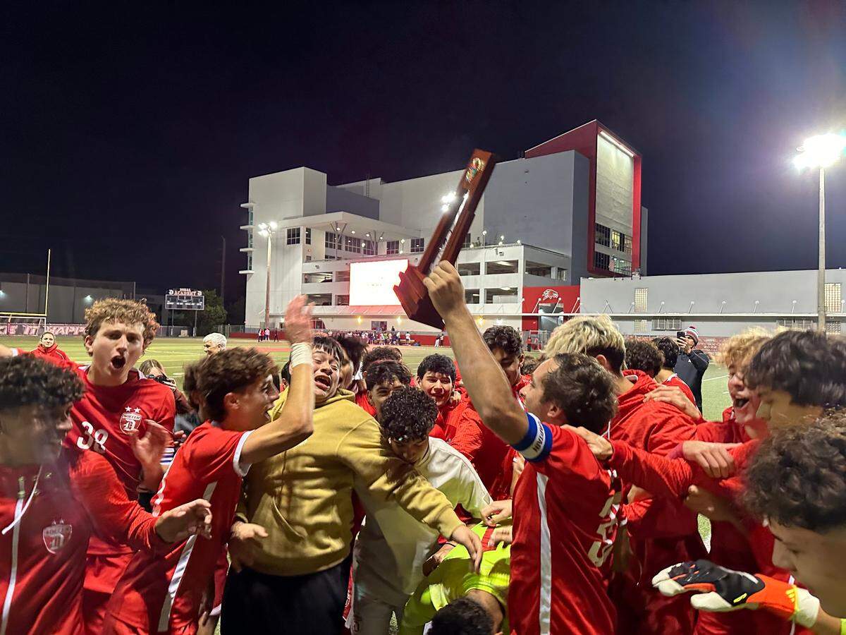 Doral Academy boys’ soccer players celebrate with the Region 4-7A championship trophy after a last-minute comeback to beat Cypress Bay on Wednesday night.