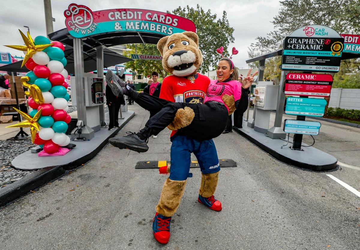 El Car Wash employee Dianelis Reina is carried by Florida Panther’s mascot Stanley C. Panther during the company’s celebration of its expansion to over 50 locations in Florida and Michigan.