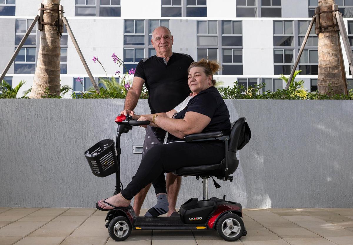 Milagros Mesa, de 68 años, que usa una patineta eléctrica para desplazarse debido a la polio que padece desde la infancia, y su marido, Fidel Valdés, de 65 años, en su nuevo apartamento el martes 19 de noviembre de 2024, en el downtown de Miami. La pareja fue desplazada a principios de este año después que Temple Court Apartments, donde vivían, se incendió y fue demolido.