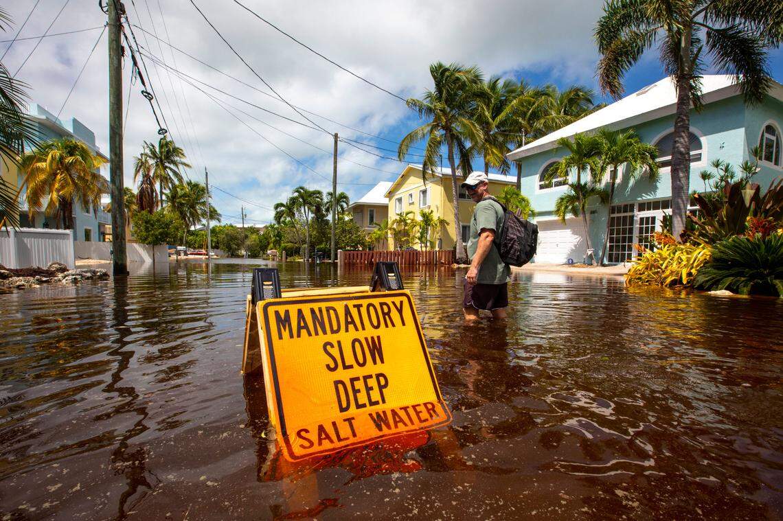 Resident CJ Ferguson walks past a sign that reads ‘ MANDATORY SLOW DEEP SALT WATER’ during flooding due to Hurricane Ian at Stillwright Point in Key Largo, Florida, on Thursday, Sept. 29, 2022.