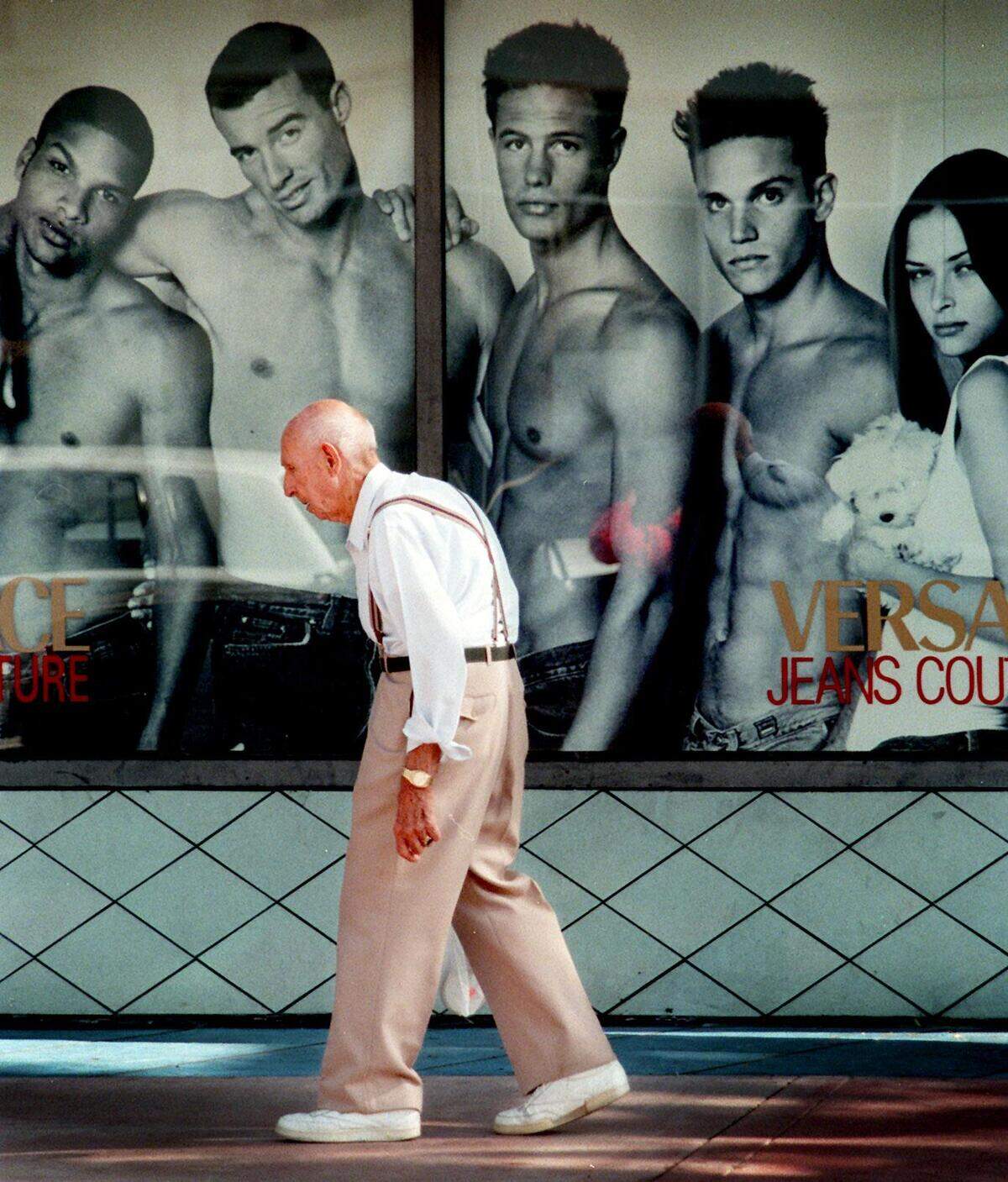 11/18/97 Patrick Farrell/Miami Herald Setting his own style...Thumbing his nose at South Beach’s Skin Culture, a morning shopper trudges past the Versace billboard that shows more flesh than fashion outside the Versace store on Washington Avenue in Miami Beach...
