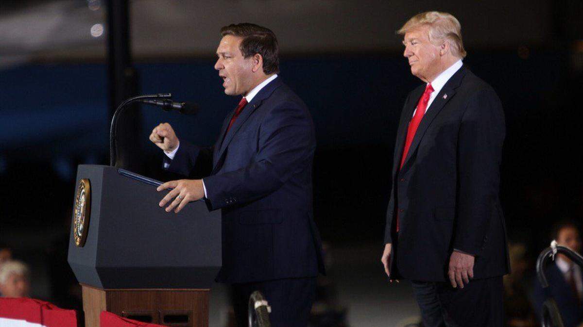 President Donald Trump listens as Ron DeSantis speaks Saturday, Nov. 3, 2018, at a rally at the ST Engineering hangar at the Pensacola International Airport.
