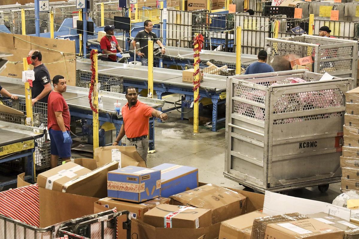 Postal workers process holiday packages at the Royal Palm Processing and Distribution Center on Thursday, December 19, 2019.