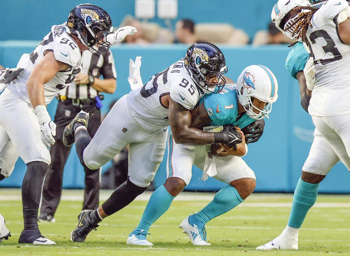 Miami Dolphins quarterback Tua Tagovailoa (1) is sacked by Jacksonville Jaguars defensive end BJ Green II (95) in the first half of an NFL football game at Hard Rock Stadium in Miami Gardens, Florida, on Saturday, August 23, 2025.