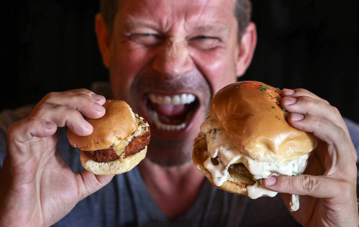 Alexander Ringleb of Burgermeister, a restaurant specializing in small-bite burgers in Miami's Brickell neighborhood, holds a small chicken sandwich alongside a regular-sized burger on Thursday, May 8, 2028.